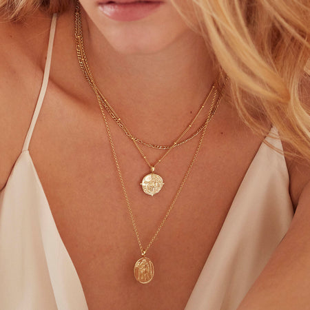 Model wearing layered gold Athena and Aphrodite necklaces.